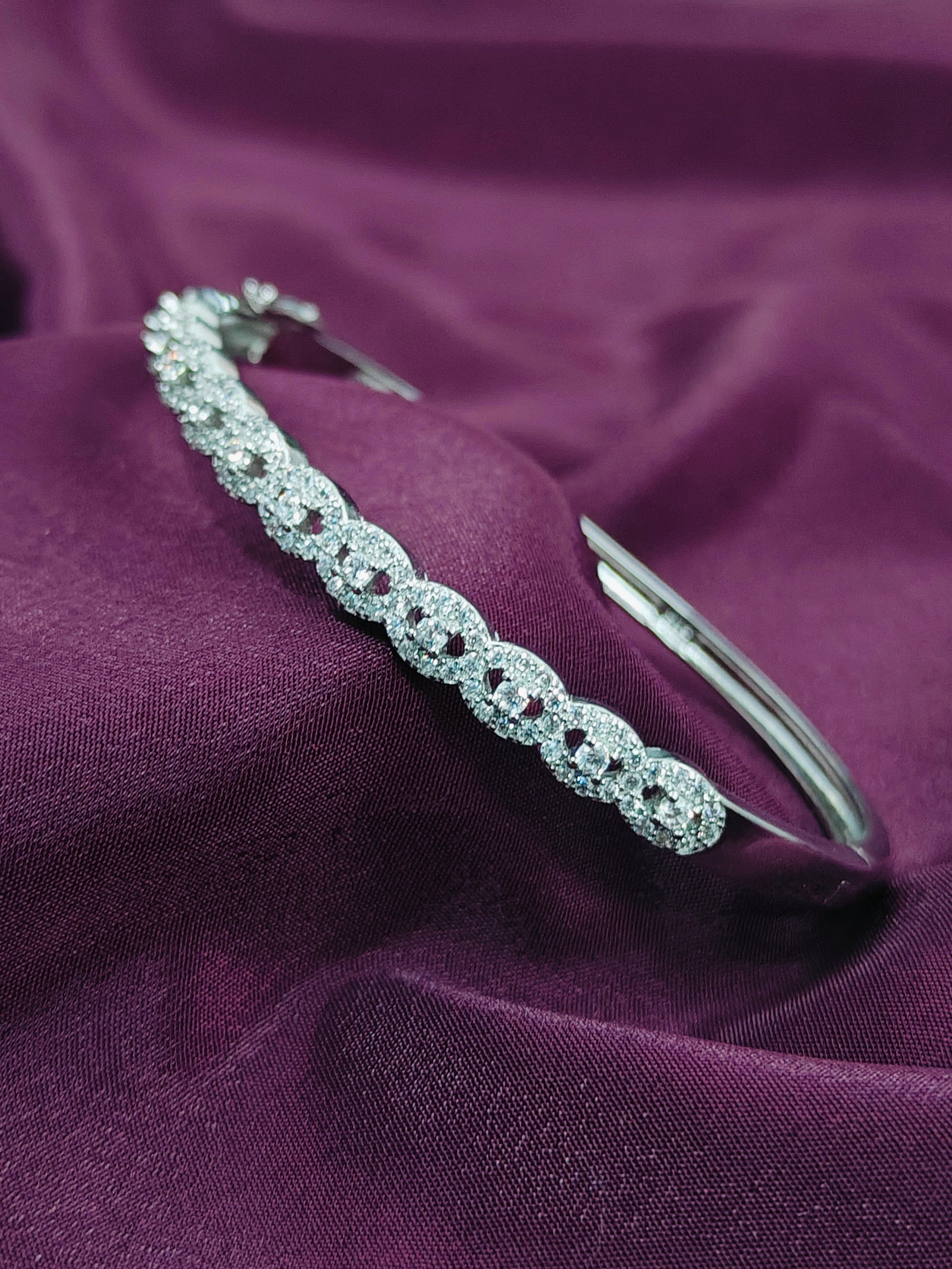 Silver bracelet with clear stones on a purple fabric background